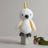 White and yellow stuffed toy on a wooden block with a minimal background