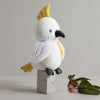 Knitted parrot toy on a wooden block with a minimal background