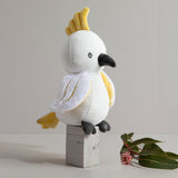 Knitted parrot toy on a wooden block with a minimal background