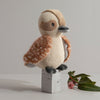 Knitted owl toy on a wooden block with a minimal background