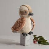 Knitted owl toy on a wooden block with a minimal background