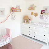 Children's bedroom with white dresser, crib, and decorative elements.