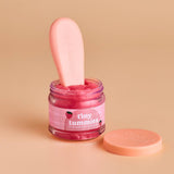 Jar of pink baby food with a spoon on a beige background