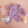 Purple children's pajama set with white floral pattern on a pink background