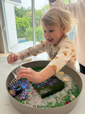 Child playing with a sensory bin filled with colorful materials