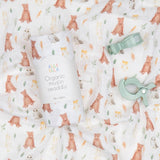Organic muslin swaddle with animal pattern and green teether on a matching fabric background