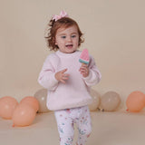 Child holding a toy ice cream cone with balloons in the background