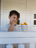 Child eating chips from a container on a white window sill