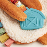 Plush toy with a teal barn-shaped tag on a soft surface