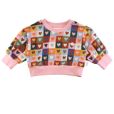 Colorful heart-patterned sweater with pink trim on a white background