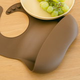 Brown silicone mat with a bowl of grapes on a wooden surface