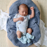 Newborn baby sleeping on a blue textured blanket with a white crib sheet.