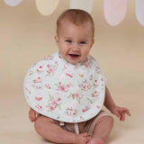Baby wearing a floral bib with a beige background