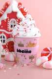 Pink hot chocolate cup with whipped cream and candy canes against a pink background