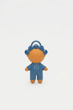 A small stylized doll figure with an orange face and limbs, wearing a blue ribbed outfit and blue flower-like hair accessories, standing against a plain white background.