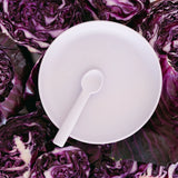 White plate with a spoon surrounded by purple cabbage