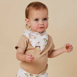 A baby wearing a beige short-sleeve top and a white bib with a vintage-style illustrated print, standing against a solid beige background.