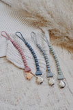 Four colorful pacifier clips on a textured surface