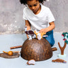 Child playing with wooden animal toys on a large brown dome-shaped object.