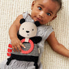 Baby holding a panda-shaped toy on a textured surface