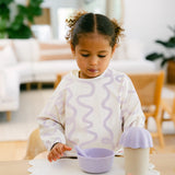 Child wearing a bib with wavy pattern in a home setting