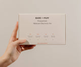 Hand holding a 'Bare Mum' postpartum skincare discovery set against a plain background