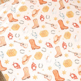 A close-up of a western-themed patterned surface featuring watercolor-style cowboy boots, hats, guitars, horseshoes, stars, and bandanas on a light cream background.