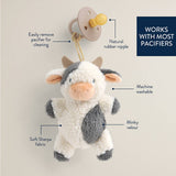 Cow-shaped pacifier clip with features highlighted on a beige background
