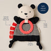 Panda-shaped toy with textured ribbon and pink ring on a beige background