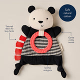 Panda-shaped toy with textured ribbon and pink ring on a beige background