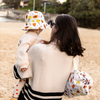 Woman holding a child wearing a colorful hat on a beach