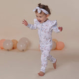 Child wearing a floral onesie with balloons in the background