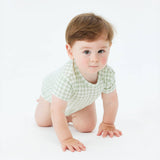 Baby in a green checkered onesie crawling on a white surface