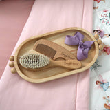 Close-up of Snuggle Hunny natural wooden baby hairbrush showing soft nylon bristles and engraved handle.