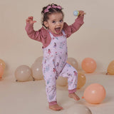 Child in a floral outfit surrounded by balloons on a beige background