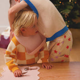 Two children playing at a table with a blurred Christmas tree in the background