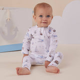 Baby wearing a patterned onesie sitting on a light-colored surface with a neutral background