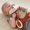 Baby holding a soft toy with a monkey design on a beige surface