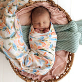 Newborn baby swaddled in colorful blanket in a wicker basket