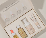 Skincare product set with bottles and a box labeled 'Postpartum Skincare Routine'.