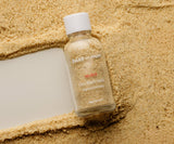 Bottle of Bare Mum bath salts on a textured beige surface