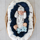Newborn baby in a crib with nautical-themed bedding and outfit
