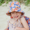 Child wearing a colorful floral bucket hat on a beach.