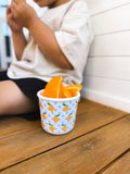 Child sitting on a wooden bench with a cup of orange slices