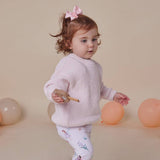 Child in a pink sweater with balloons on a beige background