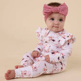 Baby in floral outfit with pink headband on beige background