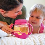 Woman and child with a pink cup containing a clear liquid on a white surface