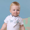Baby wearing a white shirt with floral design and a blue background