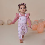 Child wearing a pink floral outfit with balloons in the background