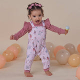 Child wearing a pink floral outfit with balloons in the background